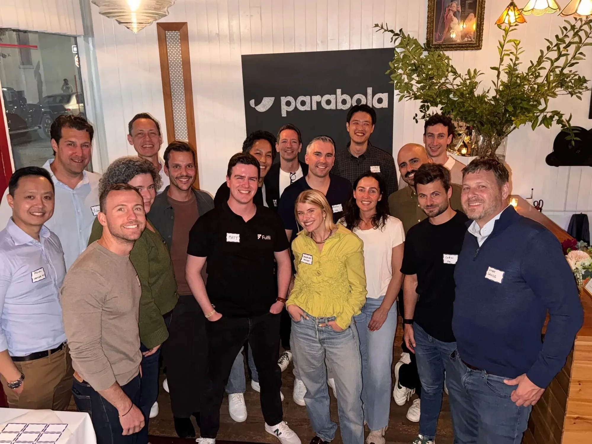 About twenty SOP Community members smiling together at a Parabola dinner, in front of a Parabola banner